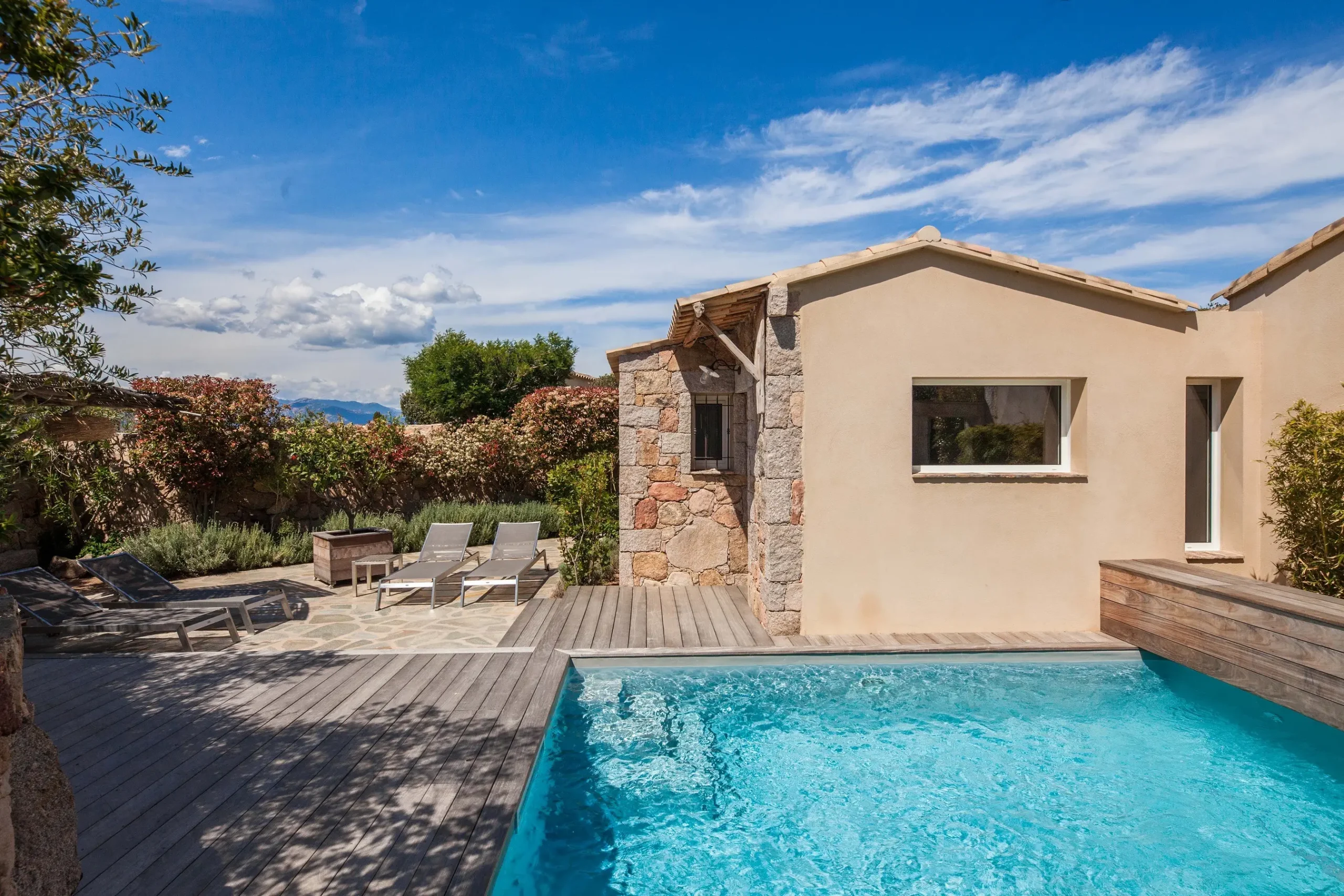 Extérieur d'une bergerie de luxe en pierre avec piscine privée et terrasse sous le soleil de Corse.