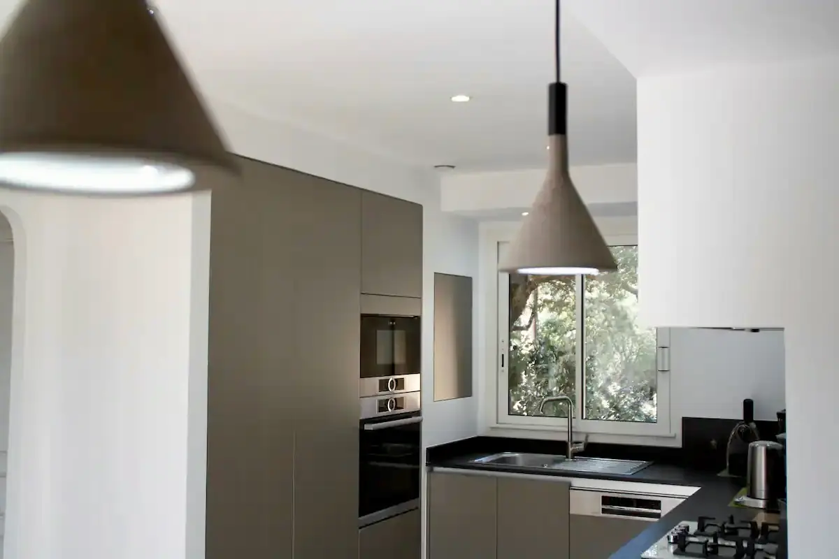 Cuisine moderne haut de gamme entièrement équipée avec îlot central et luminaires design dans une villa de luxe à Porto-Vecchio.