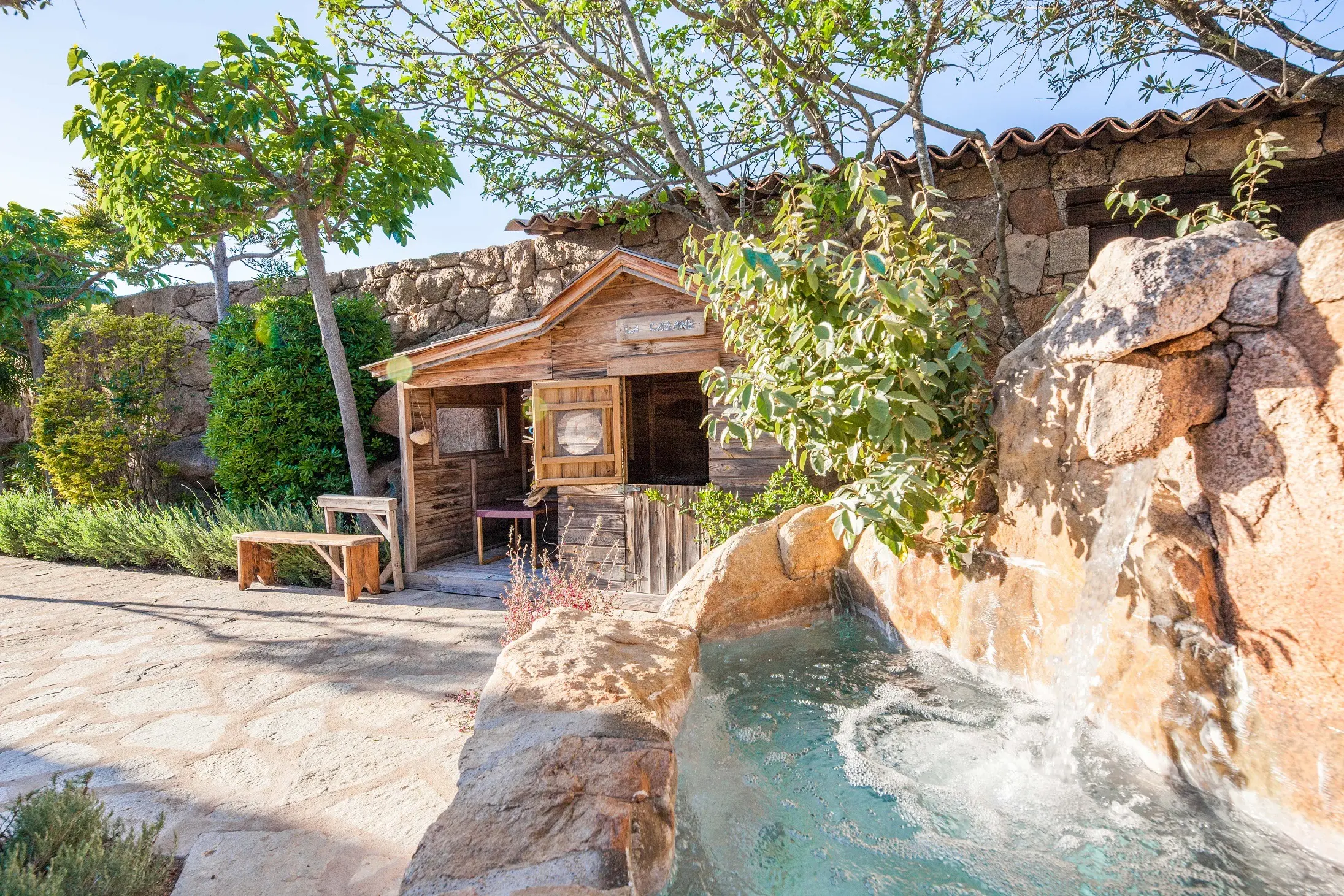 Aire de jeux pour enfants avec cabane en bois et balançoire dans le jardin d'une villa de luxe à Porto-Vecchio.